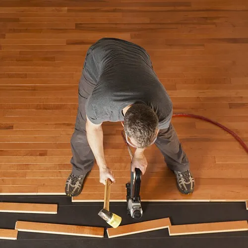 Worker installing hardwood floor | Flooring By Design