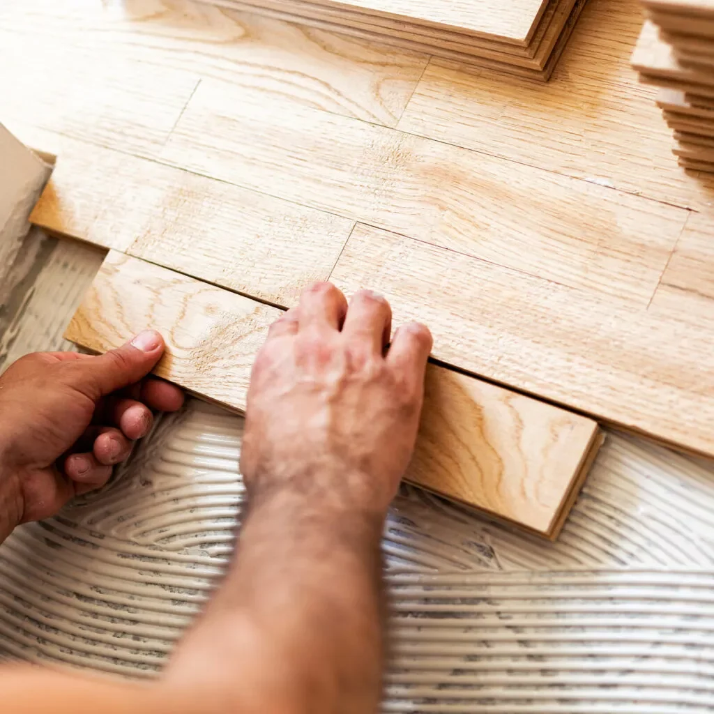 Worker installing hardwood | Flooring By Design